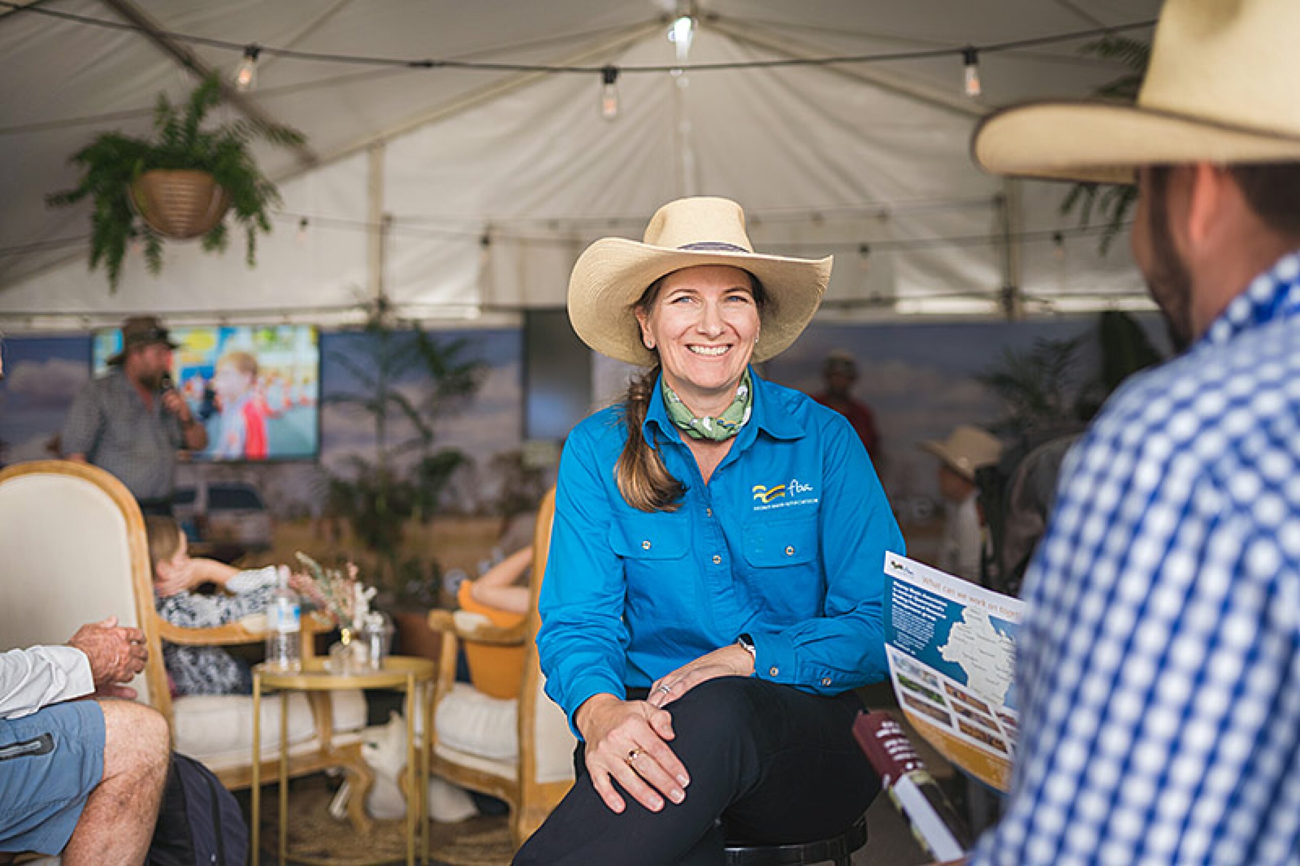 FBA staff member sits in an event space talking to a member of the public.
