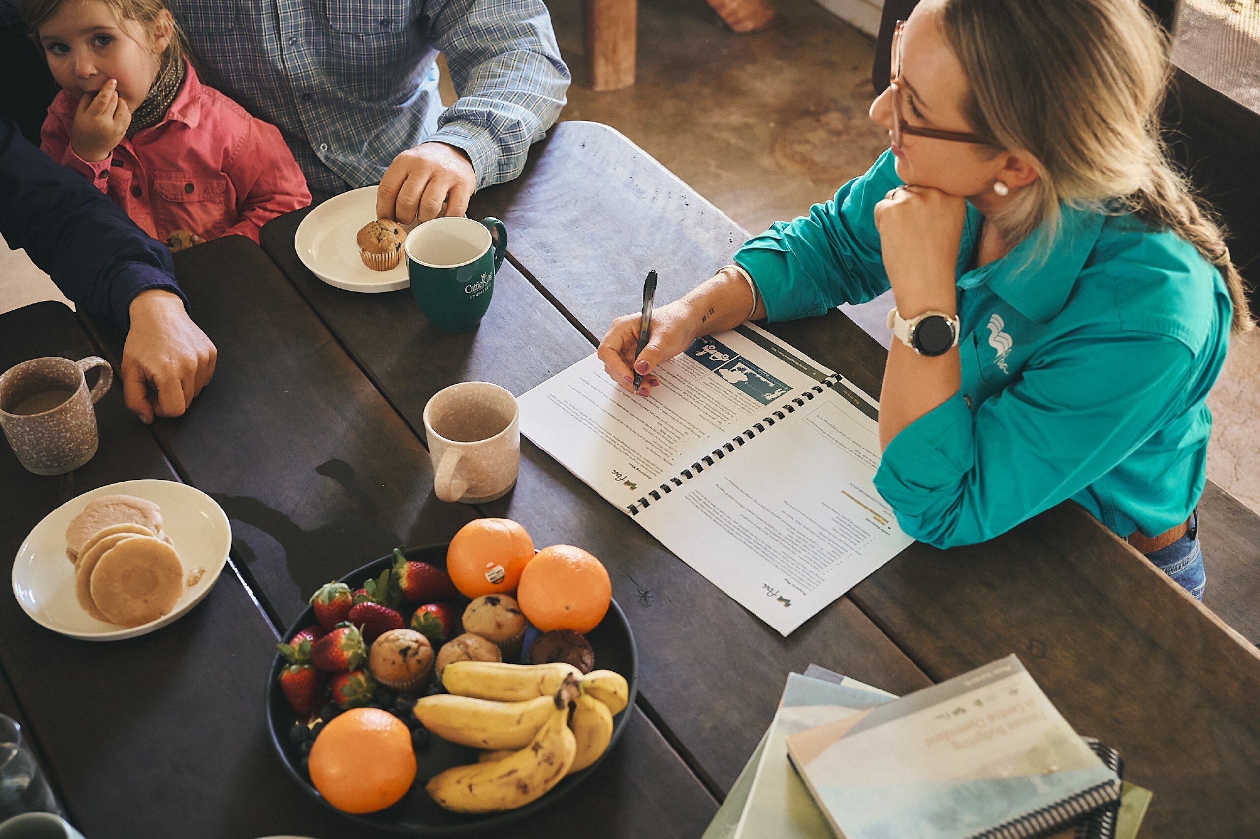 An FBA staff member discusses information from a document at a table with a farming family.